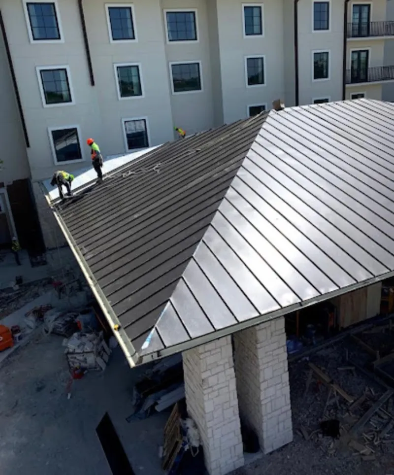 Crew installing standing seam metal roof panels on a commercial project in South Windsor